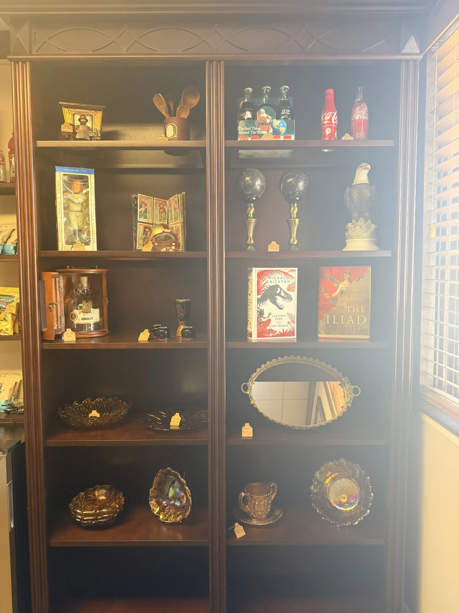 Wooden display cabinet holding books and decorative trinkets