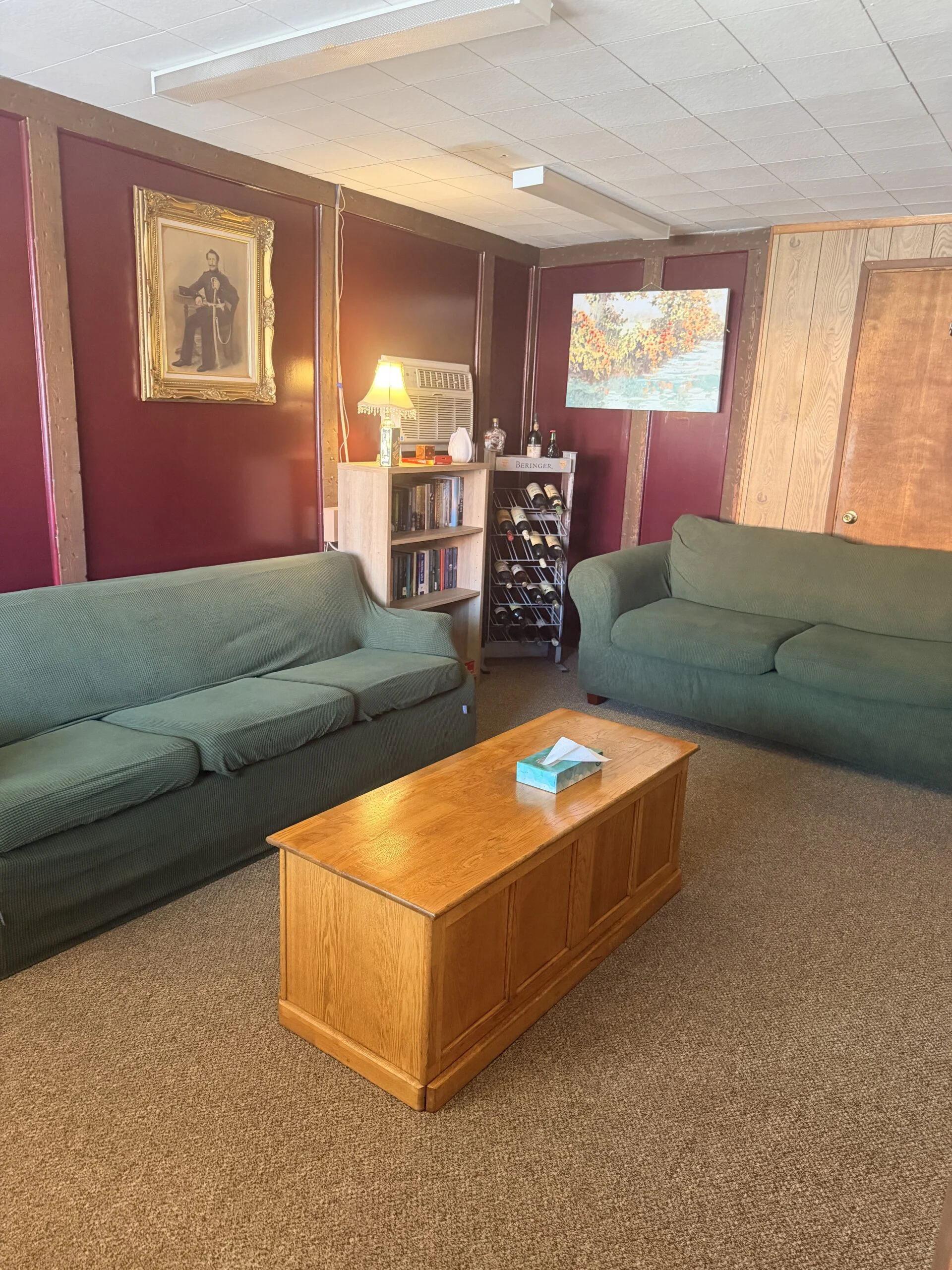 Lounge area with green sofas, wooden coffee table and framed art