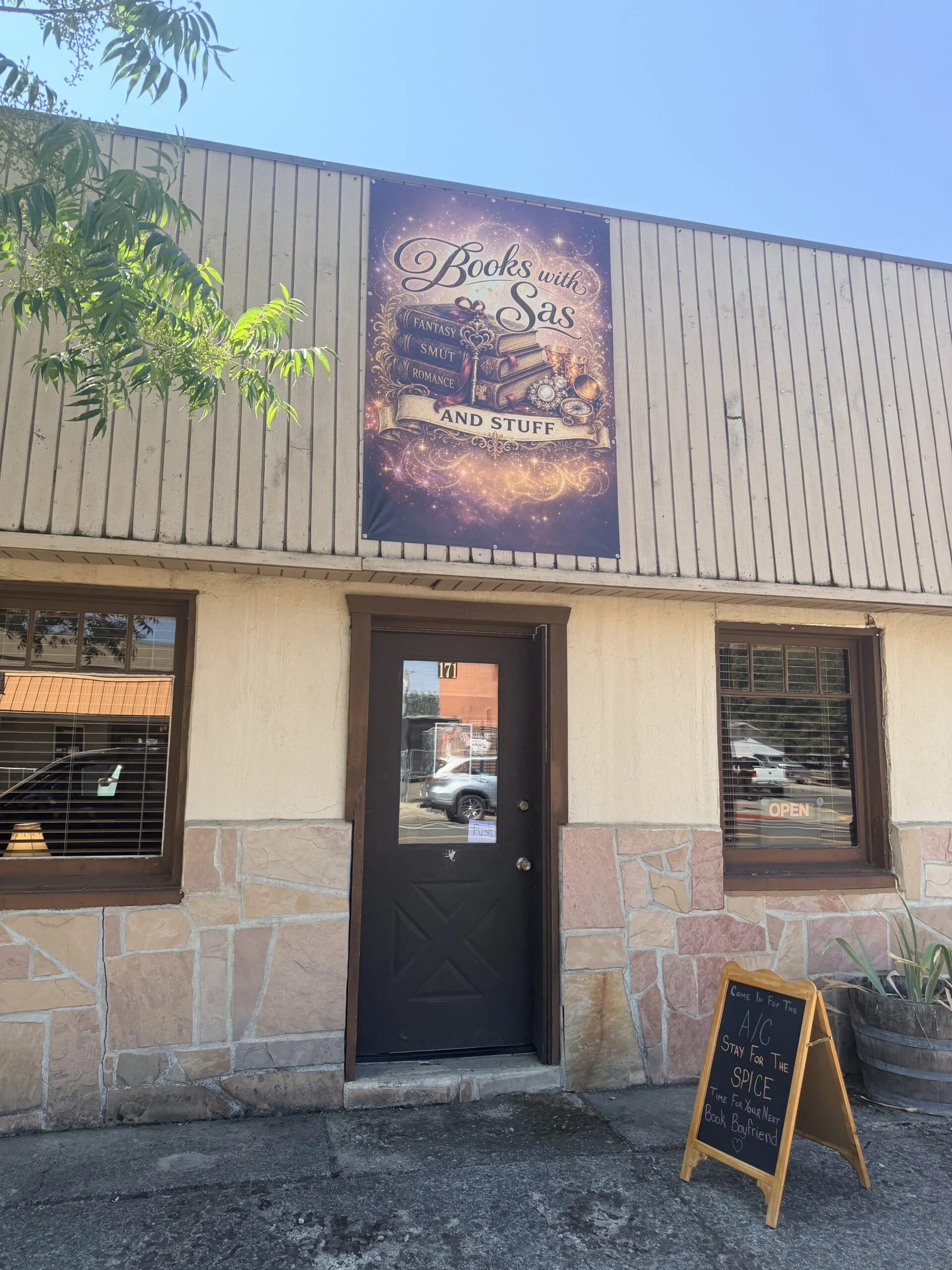 Books with Sas storefront with banner sign and sidewalk chalkboard